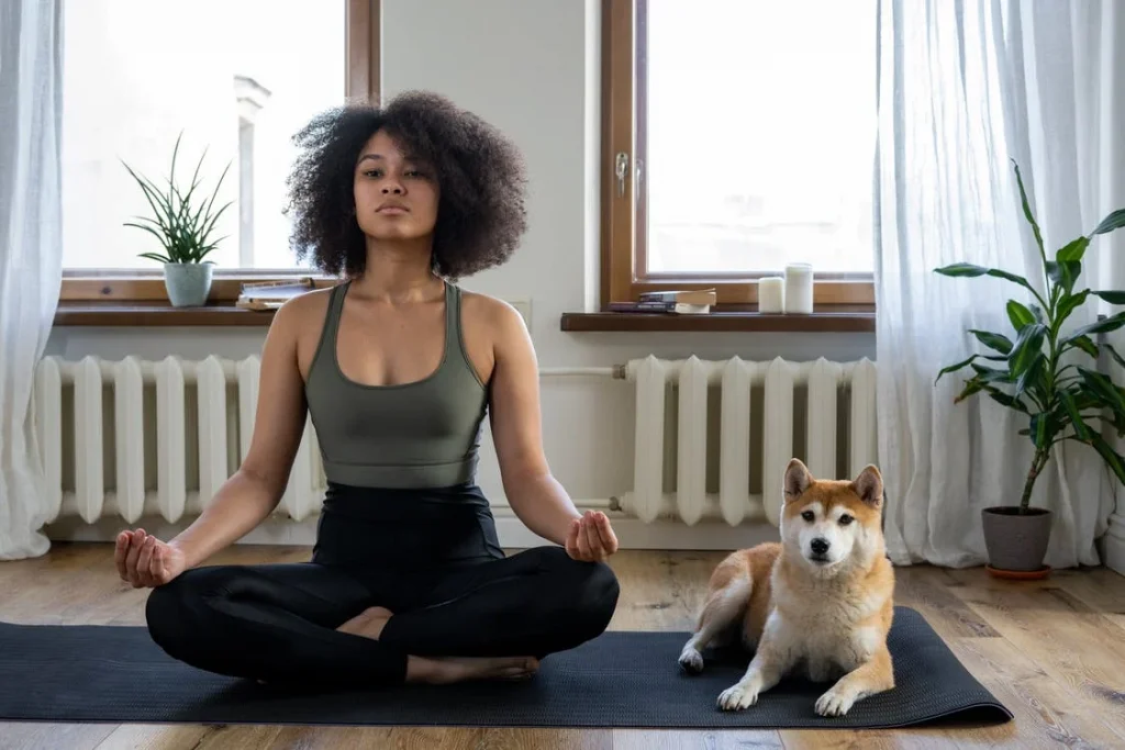 a lady sitting on mat with a dog